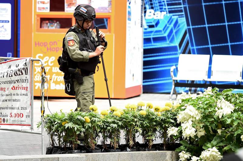A policeman from the explosive ordinance disposal unit runs a bomb detector through a bed of flowers at the scene of an explosion in Bangkok. Two people were injured as at least two small explosions hit Bangkok, police said, as the political febrile country hosts a regional summit attended by US Secretary of State Mike Pompeo.  AFP