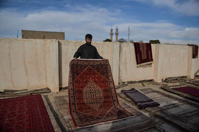 A worker arranges rugs to be dried on the rooftop of a washing factory in Herat, Afghanistan. AFP