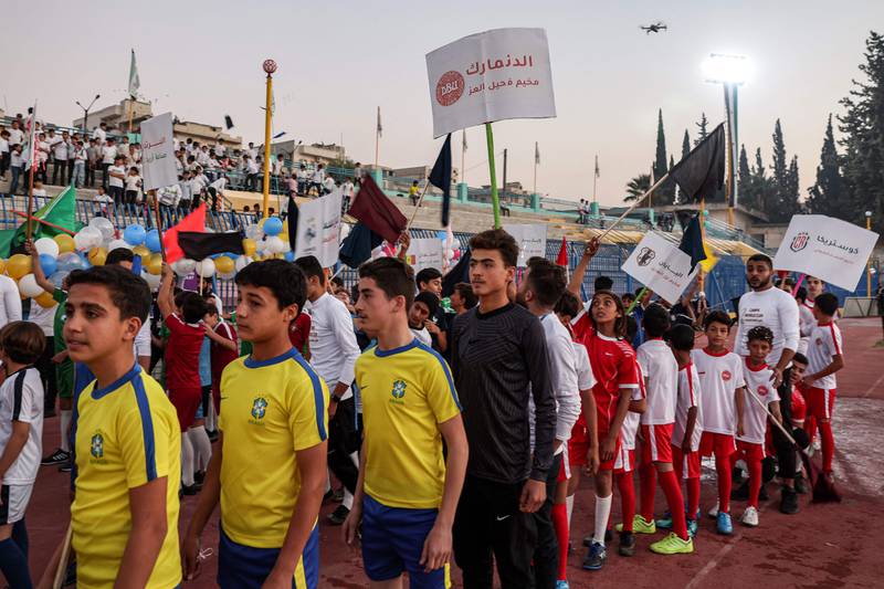 Excited children take part in the opening ceremony at the municipal stadium in Idlib, north-west Syria, wearing the jerseys of this year's World Cup teams