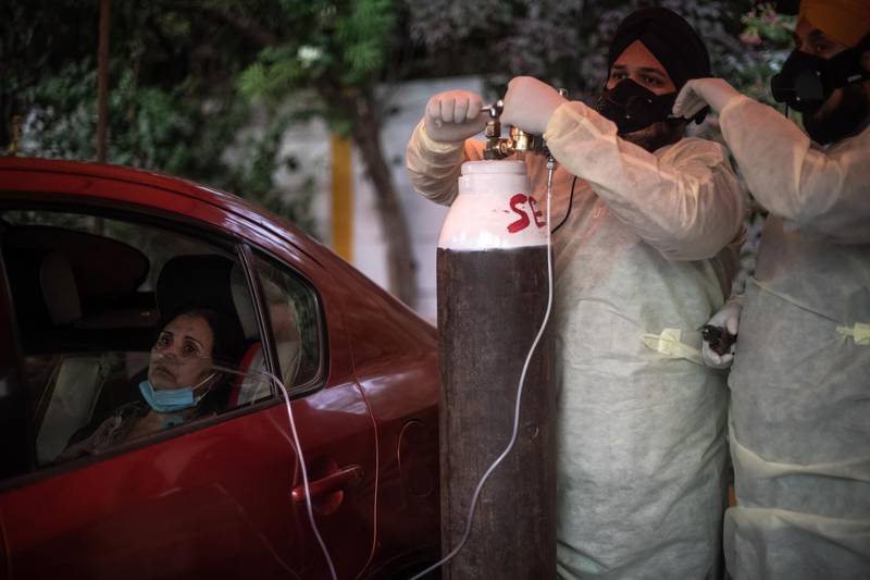 NEW DELHI, INDIA - MAY 03: Volunteers treat patients suffering from Covid-19 with free oxygen at a makeshift clinic in a parking lot outside the Gurdwara Damdama Sahib on May 03, 2021 in New Delhi, India. India recorded more than 360,000 coronavirus cases in a day for the 12th day in a row as the total number of those infected according to Health Ministry data neared 20 million. The real figure could be up to ten times higher, many health experts say, due to a lack of widespread testing or reporting, and only patients who succumbed in hospitals being counted. A new wave of the pandemic has totally overwhelmed the country's healthcare services and has caused crematoriums to operate day and night as the number of victims continues to spiral out of control. (Photo by Rebecca Conway/Getty Images)
