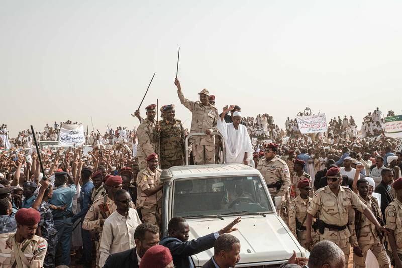 Mohamed Hamdan Dagalo (C), known as Himediti, deputy head of Sudan's ruling Transitional Military Council (TMC) and commander of the Rapid Support Forces (RSF) paramilitaries, waves a baton to supporters on a vehicle as he arrives for a rally in the village of Abraq. AFP