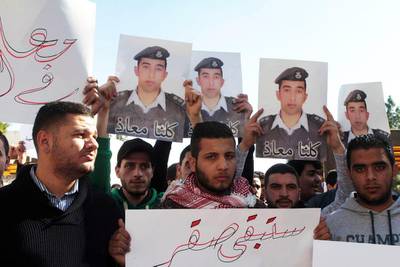Students hold a sign reading in Arabic, 'You will stay a Falcon' and pictures of Maaz Al Kassasbeh in Amman. EPA 


