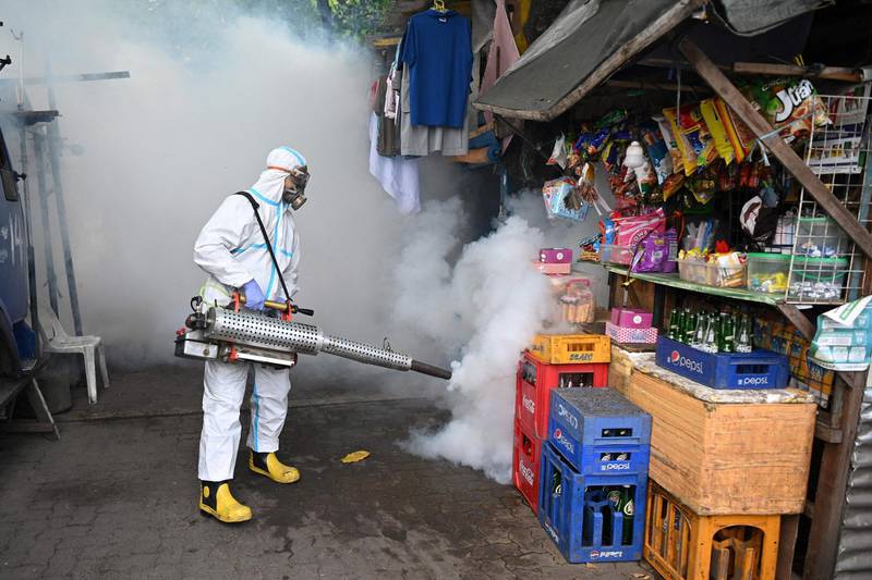 A city employee disinfects houses at an informal settlers area in Manila on March 16, 2021, as the number of new daily cases of Covid-19 coronavirus has surged to the highest level in seven months.  AFP