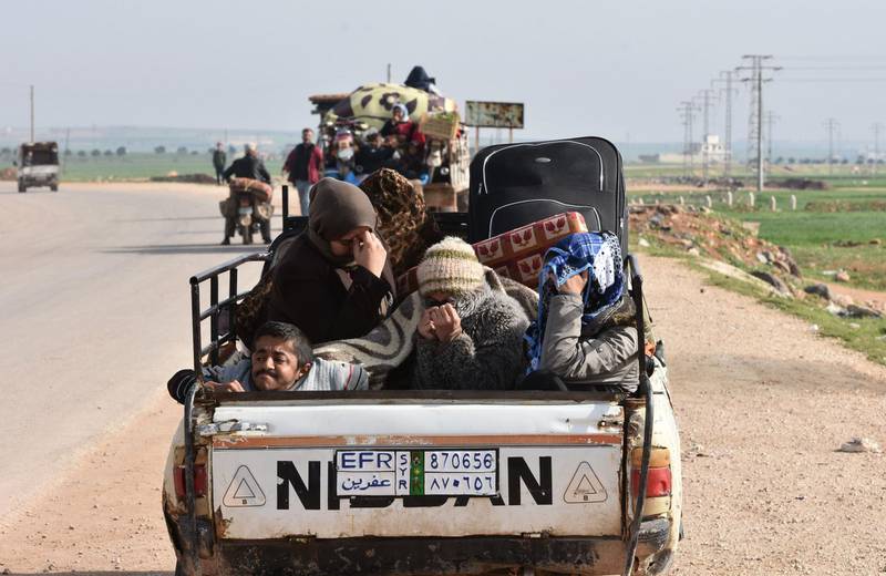 Civilians fleeing the city of Afrin in northern Syria are seen on the back of a pick up truck as they enter the village of Tal Rifaat in the government-controlled part of the northern Aleppo province, on March 18, 2018. George Ourfalina / AFP