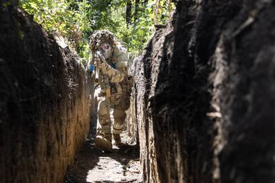 A Ukrainian soldier with the 110th Brigade demonstrates tactical movements in a trench, in Novodarivka, Luhansk region, in July. Getty Images
