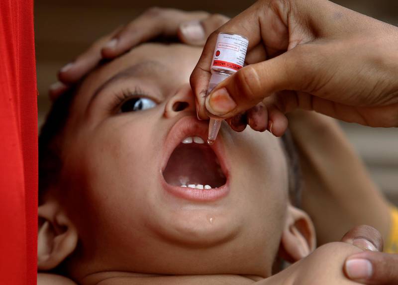 A health worker administers a polio vaccine to a child, in Karachi, Pakistan, Wednesday, June 9, 2021. Gunmen on a motorcycle Wednesday shot and killed two police officers assigned to protect polio vaccination workers in the district of Mardan in Khyber Pakhtunkhwa province, northwest Pakistan before fleeing, police said. (AP Photo/Fareed Khan)