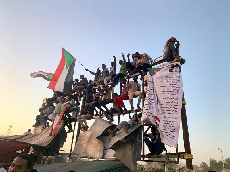 Protesters perched on a billboard frame at the sit-in outside the headquarters of Sudan's armed forces in Khartoum. Hamza Hendawi for The National