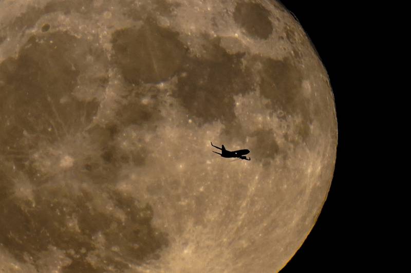 A plane passes in front of a full moon Wednesday, July 13, 2022, in Milwaukee.  The moon's orbit brought it closer to Earth than usual.  This cosmic combo is called a supermoon.  One name for Wednesday’s full moon is  the “Buck moon”==a reference to the time of year when new antlers are growing on male deer, or bucks.  (AP Photo / Morry Gash)
