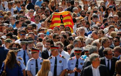 People holding a Catalan flag gather for a minute of silence in memory of the terrorist attacks victims in Las Ramblas, Barcelona, Spain, Friday, Aug. 18, 2017. Spanish police on Friday shot and killed five people carrying bomb belts who were connected to the Barcelona van attack that killed at least 13, as the manhunt intensified for the perpetrators of Europe's latest rampage claimed by the Islamic State group. (AP Photo/Francisco Seco)
