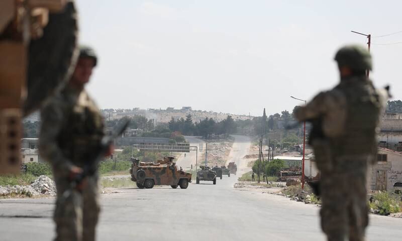Turkish soldiers keep watch as vehicles from a joint Russian-Turkish patrol pass through the outskirts of the rebel-held town of Ariha in Syria's north-west Idlib province.
