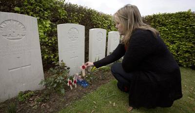 Kaylene Biggs, great-granddaughter Australian soldier Andrew Bayne, places a wooden cross with a poppy and a message on the grave at Westhof Farm Commonwealth Cemetery in Nieuwkerke, Belgium. AP Photo