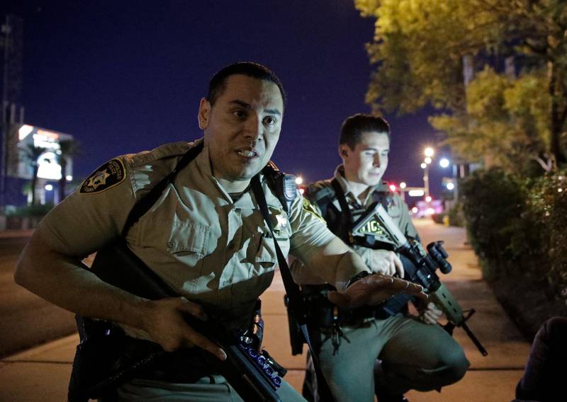 
                  Police officers advise people to take cover near the scene of a shooting near the Mandalay Bay resort and casino on the Las Vegas Strip, Sunday, Oct. 1, 2017, in Las Vegas. (AP Photo/John Locher)
               
