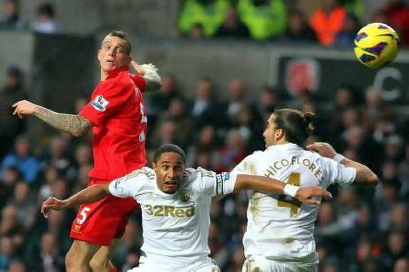 Liverpool`s Daniel Agger, left, leaps above Swansea City's Ashley Williams, centre, and Chico Flores, right. Geoff Caddick / EPA