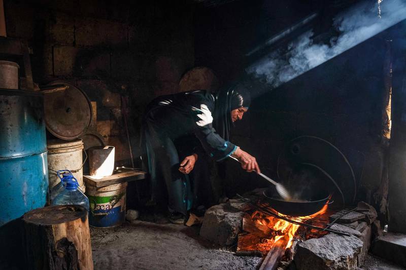 EDITORS NOTE: Graphic content / TOPSHOT - A woman fries potatoes as she prepares the fast-breaking "Iftar" meal, consumed after sunset during the Muslim holy month of Ramadan, in a common room used by multiple marginalised families living in the Ghoraba (Strangers) cemetery, named after the neighbourhood where it is situated in Lebanon's northern port city of Tripoli on April 14, 2021. People started settling in the "Ghoraba" cemetery back in 1955, due to a flooding of the Kadisha (Abu Ali) which runs through Tripoli. Gradually over the years, poor people from across northern Lebanon, like Akkar and Donnieh followed, illegally building dwellings in layers during the civil war and its tumultuous periods of chaos. Since 2019 and until now, the graveyard is overflowing with residents and can no longer accept more newcomers, where already 120 disadvantaged Lebanese families and some 30 other Syrian ones compete with the dead for a place of rest. Some of its marginalised residents work mainly in Tripoli's cleaning industry while others totally rely on external aid. Most of the child inhabitants were born there. / AFP / Ibrahim CHALHOUB
