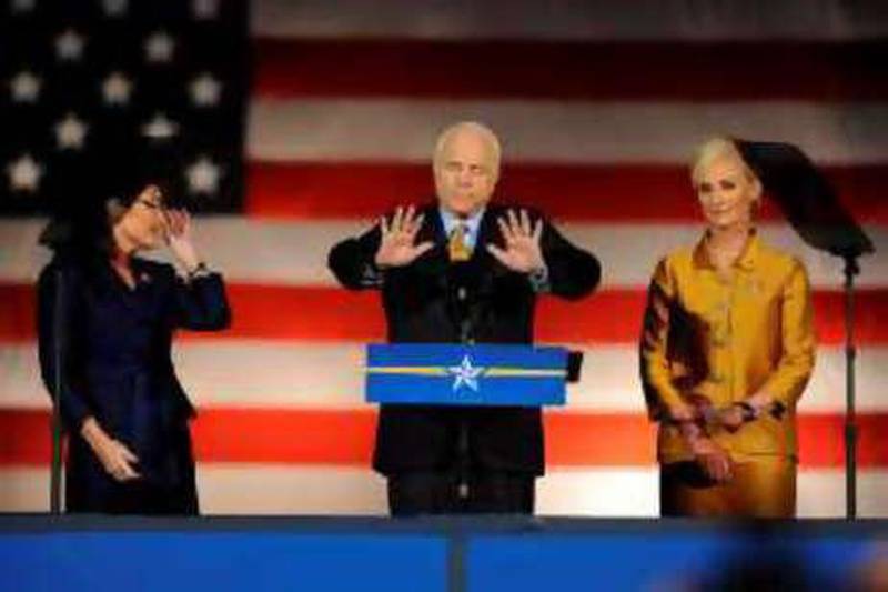 John McCain tries to quieten his supporters during his concession speech as his wife, Cindy, left, and Sarah Palin look on.