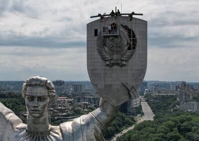 Workers remove a Soviet emblem from the Motherland monument in Kyiv, Ukraine. Reuters