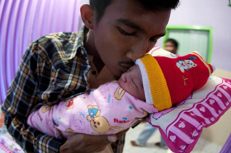 BATAM ISLAND, INDONESIA - DECEMBER 25: Kevin, father of new born Nicholas Kevin Stevanus (R), who was born at 9:30 am local time,  kissed his baby after being born on Christmas day at Tanjungpinang Hospital on December 25, 2012 in Batam Island, Indonesia. Christmas is a national holiday in Indonesia despite only eight percent of the population identifying as Christian. Muslims in Indonesia celebrate the birth of Jesus and Hindu's in the country also commemorate the date. (Photo by Yuli Seperi/Getty Images)