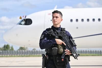 A security officer in stands in front of the plane. PA