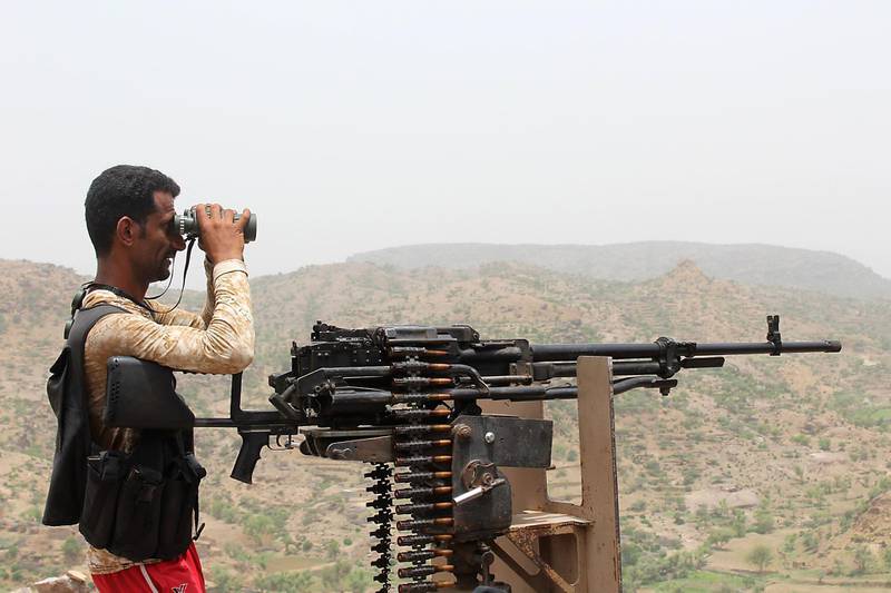 A Yemeni pro-government fighter looks through binoculars over the terrain in Kirsh.