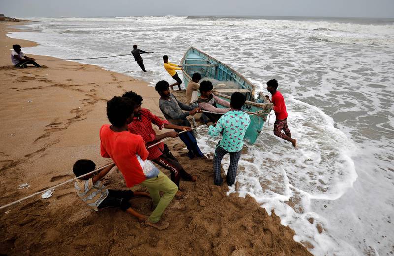 People move a fishing boat to a safer place along the shore ahead of Cyclone Tauktae in Veraval in the western state of Gujarat, India, May 17, 2021. REUTERS/Amit Dave