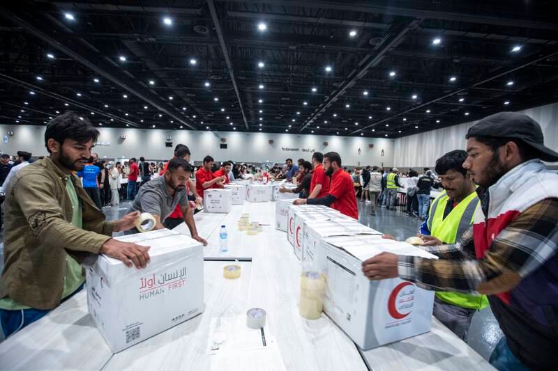 Volunteers pack food, blankets and other essential goods at the Dubai Exhibition Centre, at Expo City