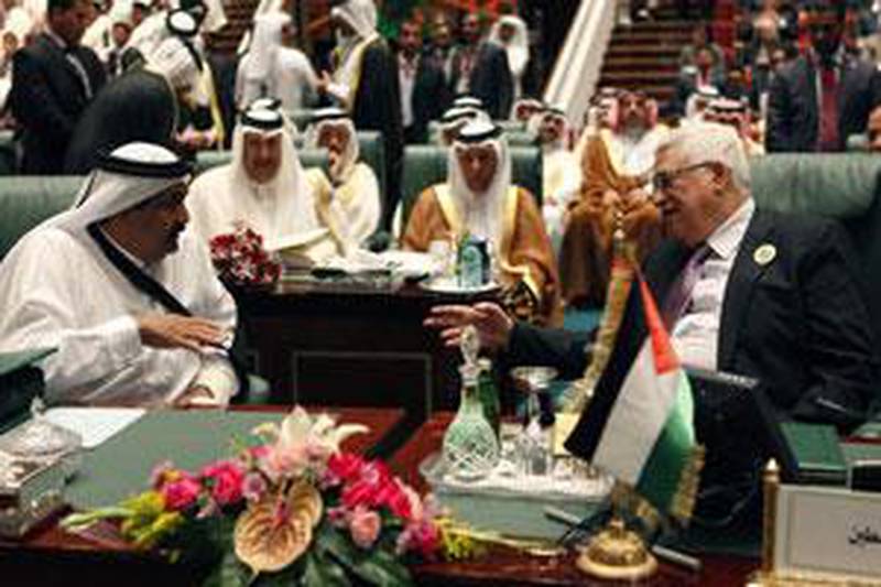 The president of the Palestinian Authority, Mahmoud Abbas, right, talks to the Emir of Qatar, Hamad bin Khalifa Al Thani, at the opening session of the Arab League summit in Sirte, Libya, yesterday.