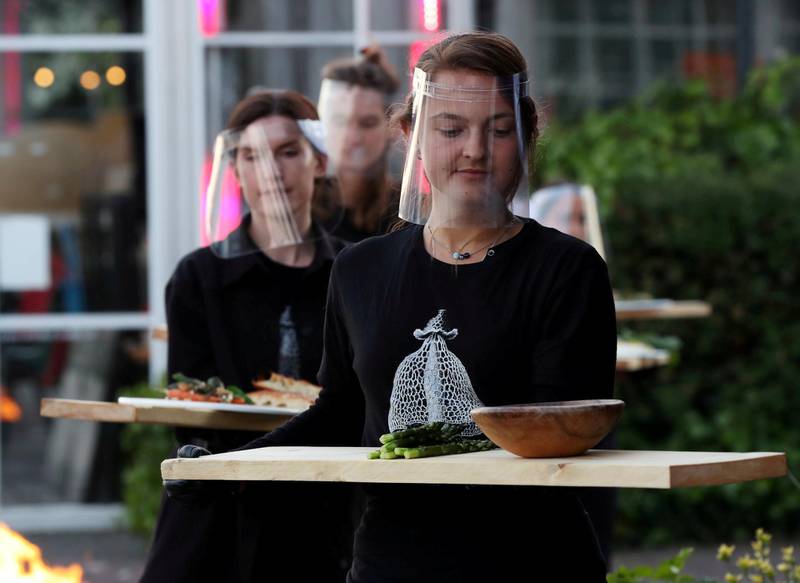 Waiters in protective gear carry food at a restaurant which is testing servers providing drinks and food to models pretending to be clients in a safe "quarantine greenhouses" in which guests can dine in Amsterdam, Netherlands. REUTERS