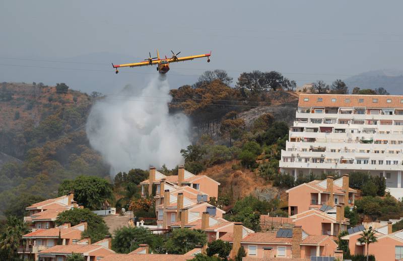 A firefighting plane drops water over buildings near a wildfire burning on the Sierra Bermeja mountains, in Estepona. Reuters
