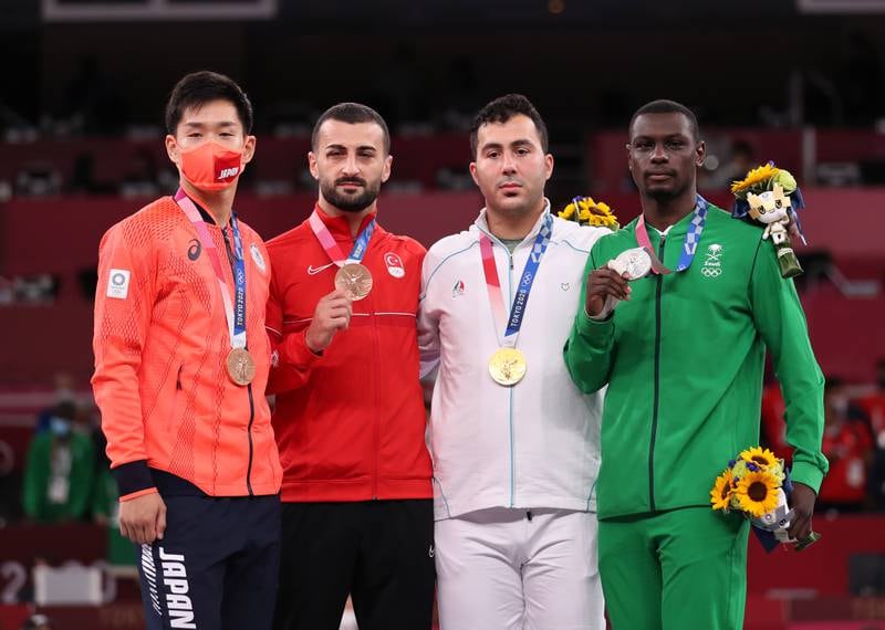 From right: Silver medalist Tareg Hamedi of Saudi Arabia, gold medalist Sajjad Ganjzadeh of Iran, and bronze medalists Ugur Aktas of Turkey and Ryutaro Araga of Japan pose on the podium during the medal ceremony for the Men's Kumite +75kg during the Karate events of the Tokyo 2020 Olympic Games at the Nippon Budokan arena.