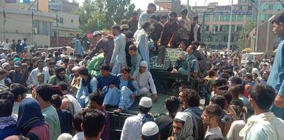 Taliban fighters and local people sit on an Afghan National Army armoured vehicle on a street in Jalalabad province on August 15, 2021. AFP