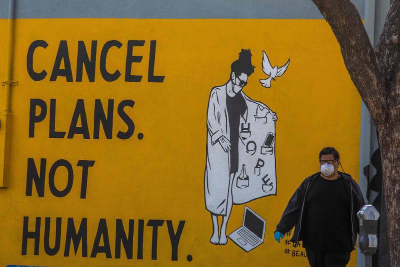 A man walks by a mural reading "Cancel Plans Not Humanity" in Los Angeles, California. AFP