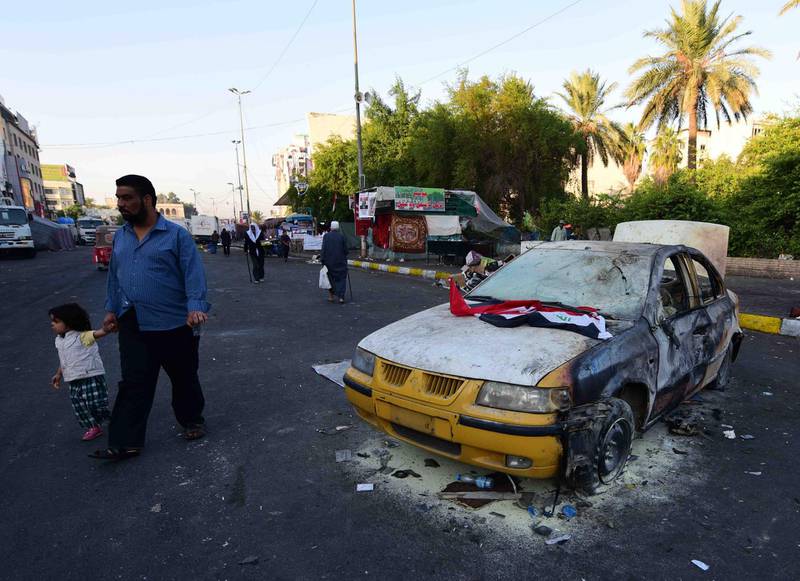 Iraqis walk past the site of a car bomb attack near Tahrir Square in central Baghdad. EPA