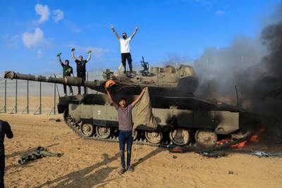 Palestinians celebrate as an Israeli tank burns after it was hit by Palestinian gunmen in southern Israel. Reuters