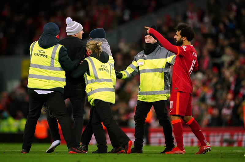 A pitch invader approaches Liverpool's Mohamed Salah after the Premier League match at Anfield, Liverpool.
