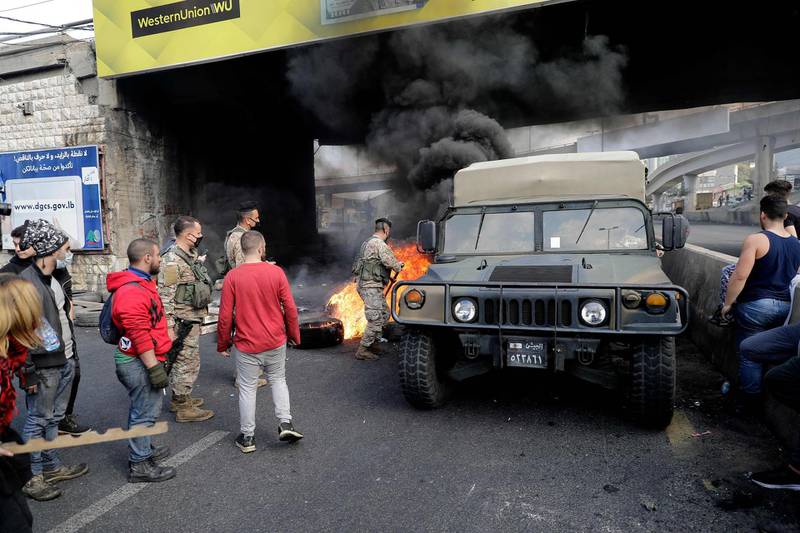Soldiers clear burning tyres set up by anti-government protesters at a makeshift roadblock in Zouk Mosbeh, north of Lebanon's capital Beirut. AFP