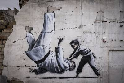 Anonymous street artist Banksy has created seven works in Ukraine, including this image of a child in judo clothing throwing a man to the ground on a damaged building in Borodyanka. Getty 