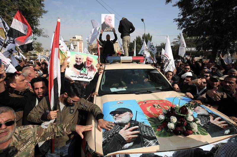 TOPSHOT - Mourners surround a car carrying the coffin of Iraqi paramilitary chief Abu Mahdi al-Muhandis (image) during a funeral procession, for him and nine others, in Baghdad's district of al-Jadriya, near the high-security Green Zone, on January 4, 2020.  Thousands of Iraqis chanting "Death to America" joined the funeral procession for Iranian military commander Qasem Soleimani and Muhandis, both killed in a US air strike. The cortege set off around Kadhimiya, a Shiite pilgrimage district of Baghdad, before heading to the Green Zone government and diplomatic district where a state funeral was to be held attended by top dignitaries. In all, 10 people -- five Iraqis and five Iranians -- were killed in Friday morning's US strike on their motorcade just outside Baghdad airport.  / AFP / AHMAD AL-RUBAYE

