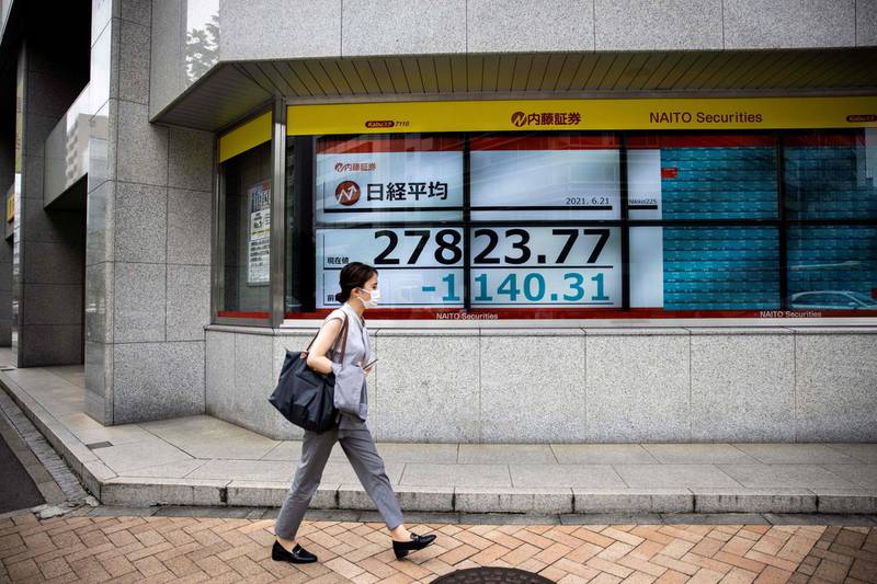 A pedestrian walks past a stock indicator displaying numbers of the Nikkei 225 of the Tokyo Stock Exchange in Tokyo on June 21, 2021. / AFP / Behrouz MEHRI
