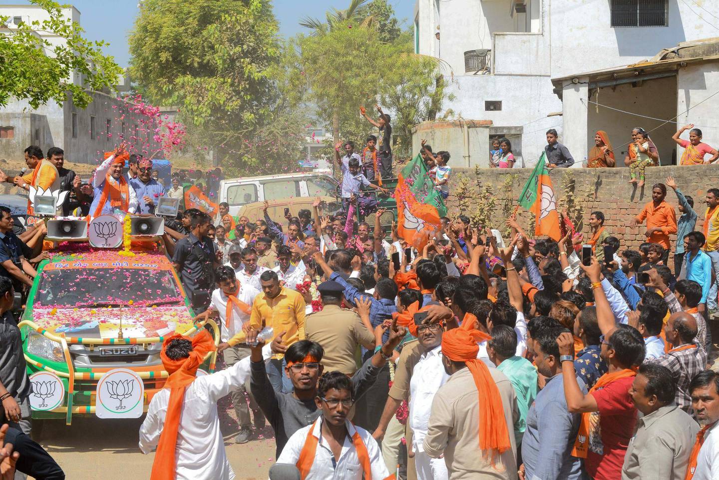 Indian Bharatiya Janata Party (BJP) National President, Amit Shah (L-C), throws floral garlands on the BJP supporters, during his road show in Ahmedabad on March 30, 2019. India is holding a general election to be held nearly six weeks starting on April 11, when hundreds of millions of voters will cast ballots in the world's biggest democracy. / AFP / SAM PANTHAKY
