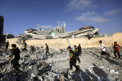 Palestinians walk by a destroyed mosque following an Israeli air strike in Khan Younis. AP