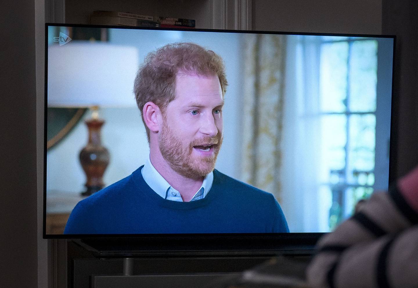 A person at home watches Prince Harry being interviewed by ITV's Tom Bradby. PA