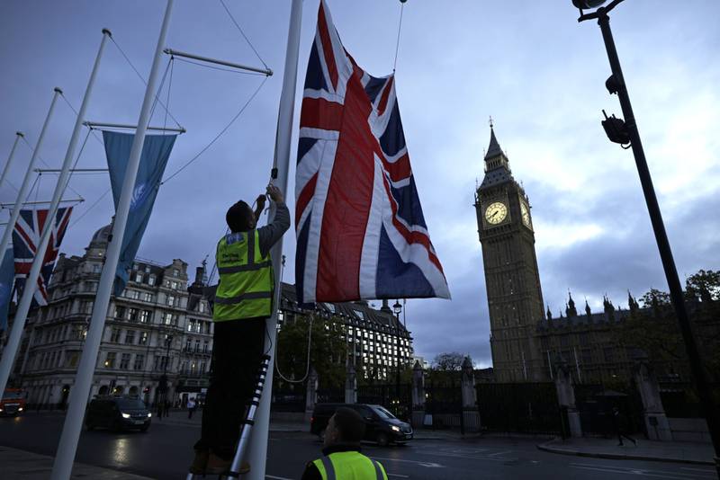 Workers raise a British Union flag on Parliament Square near the Palace of Westminster in London on Monday. Bloomberg
