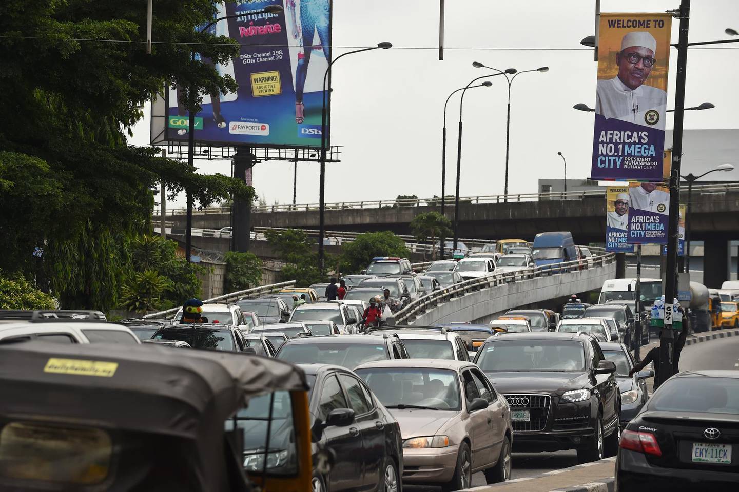 Motorists wait in a traffic jam under banners bearing a portrait of Nigeria's President Muhammadu Buhari, who is on official visit to Lagos, on March 29, 2018. - Nigeria's economic capital Lagos was on a lockdown on March 29, 2018, as Buhari makes his first official visit to the city of 22 million inhabitants since coming to power in 2015. (Photo by PIUS UTOMI EKPEI / AFP)