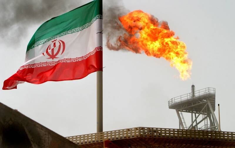 FILE PHOTO: A gas flare on an oil production platform in the Soroush oil fields is seen alongside an Iranian flag in the Persian Gulf, Iran, July 25, 2005. To match Exclusive OPEC-OIL/   REUTERS/Raheb Homavandi/File Photo/File Photo