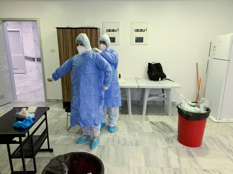 Hamza Abdulrahman Jelwal, a supervising nurse, and his teammate Aisha Milad Belhassna help each other to wear protective suits at a quarantine centre in Misrata, Libya. Reuters