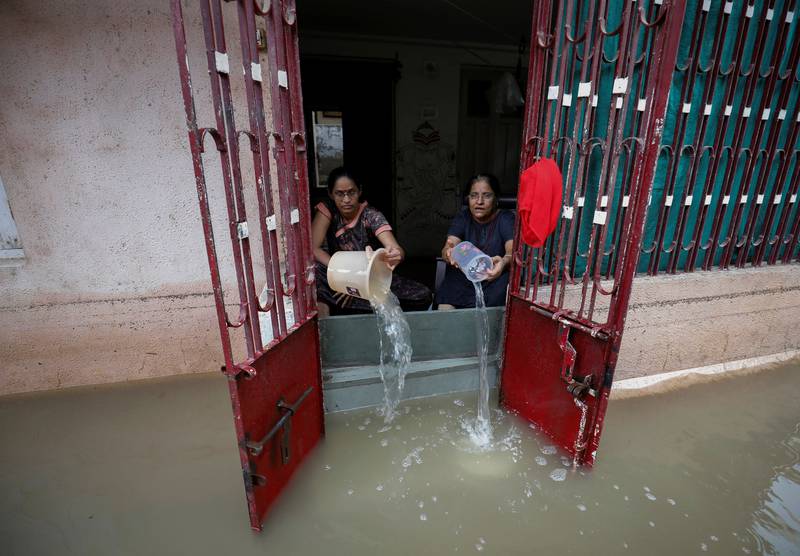 Women empty water from a house after heavy rain in Ahmedabad, India, on July 11. Reuters