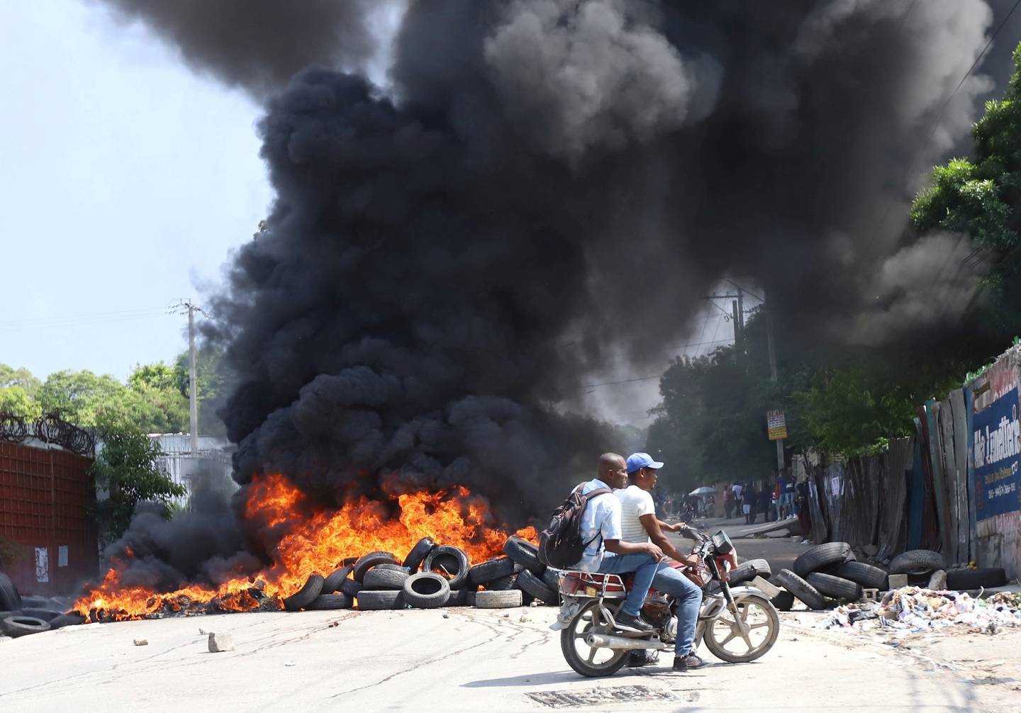 People ride on a motorcycle near a burning barricade as Haitians mount a nationwide strike to protest against a growing wave of kidnappings. Reuters