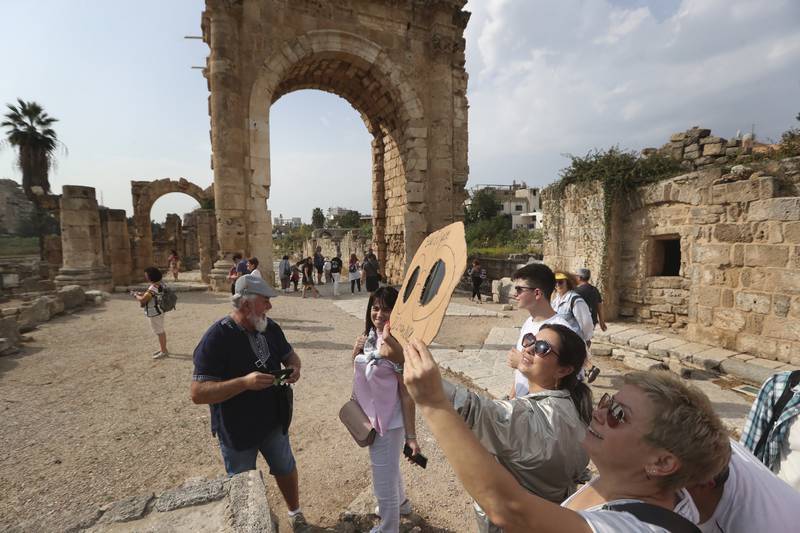 Tourists using a handmade protective viewing filter sheet to watch the partial solar eclipse, at the Phoenician ruins, in the southern port city of Tyre, Lebanon. AP