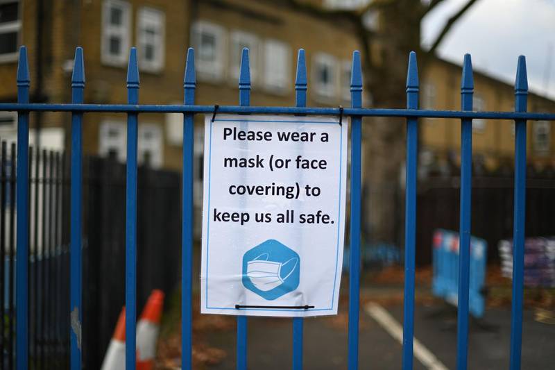 Signage reminding people to wear a mask or face covering is seen on the closed gate of a primary school in east London. AFP