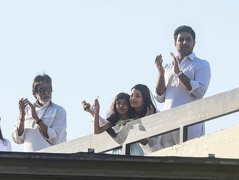 Bollywood actors Amitabh Bachchan (2L) and his son Abhishek Bachchan (R) with wife Aishwarya Rai Bachchan (2R) along with their daughter Aaradhya (3R) clap from atop a residential building to thank essential service providers during a one-day Janata (civil) curfew imposed amid concerns over the spread of the COVID-19 novel coronavirus, in Mumbai on March 22, 2020. (Photo by Sujit Jaiswal / AFP)